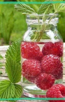 2 jars with fresh raspberries and blueberries in spring, on the table with nettle leaves around, indicating an article about 3 best herbs for spring cleaning detox.